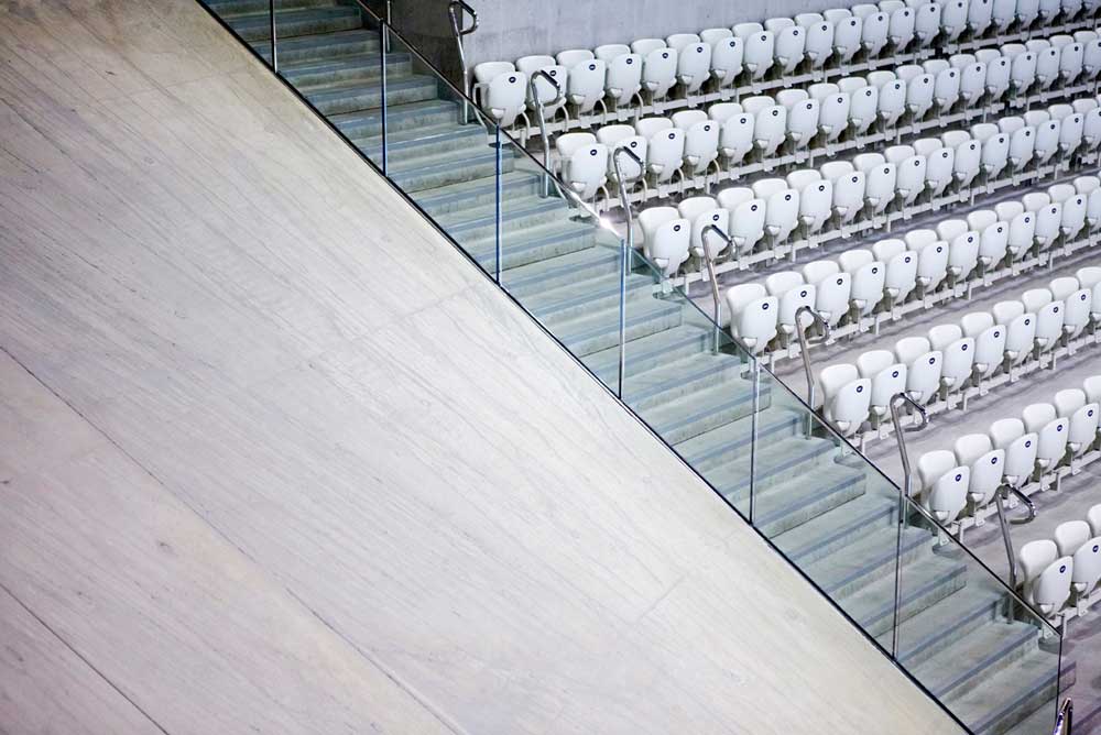 rows of empty seats and stairs at london aquatic centre by airey spaces